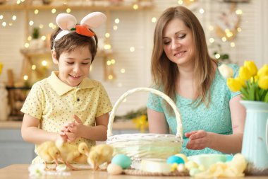 Anne ve oğul birlikte eğleniyor ve ziyafeti kutluyorlar. Aile Paskalya için hazırlanıyor. Little ve annem evi dekore ediyor. yumuşak odak