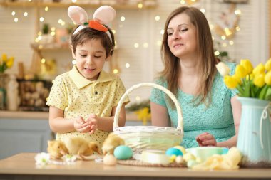 Anne ve oğul birlikte eğleniyor ve ziyafeti kutluyorlar. Aile Paskalya için hazırlanıyor. Little ve annem evi dekore ediyor. yumuşak odak