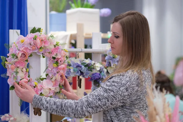 business owner selling behind counter with her bouquet of dried flowers at local market of craftsmen, small business. young woman entrepreneur sells floral holiday composition.