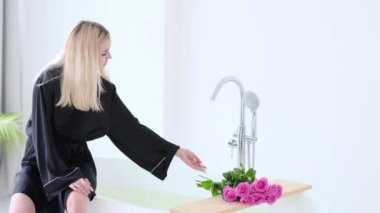 Genç ve güzel bir kadın banyoda su alıyor. Lüks Beyaz Mermer Banyo Pembe Gül ile Banyo Akan Su. Otelde romantik bir hafta sonu. Yavaş çekim videosu. Yüksek kalite stok görüntüler.
