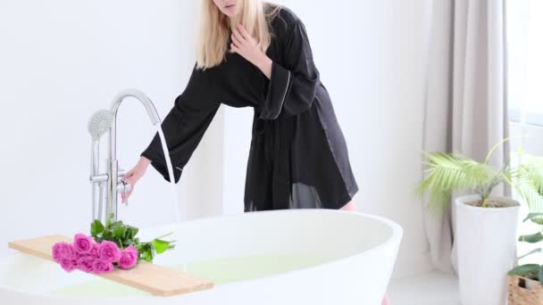 Ung vacker kvinna tar vatten i badet. Lyx vit marmor Badrum Flödesvatten till badkar med rosa ros. Romantisk helg på hotell. Slow motion-video. Högkvalitativa 4k-stockar. — Stockvideo