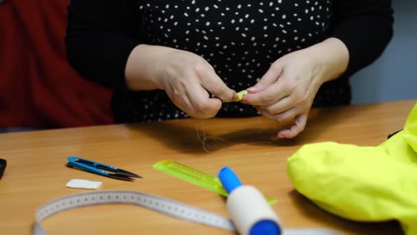 Kadın terzi elbise dikmek için tekstil işiyle uğraşıyor. Dikiş işleminin görüntüsünü kapat. Işık bulanık arkaplan — Stok video