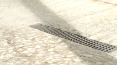 Döşeme drenajı, duşta akan su. Su akan bir duşta zeminin ağır çekimde döşenmesi. Paslanmaz çelik zemin yağmur suyuyla boşaltılıyor..