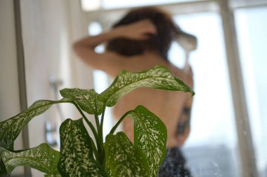 Arkadan bak. Kadın duş kabininde yıkanır, kendini rahat ve temiz hisseder, günlük rutinini unutur. İnsanlar, yaşam tarzı ve ferahlatıcı konsept