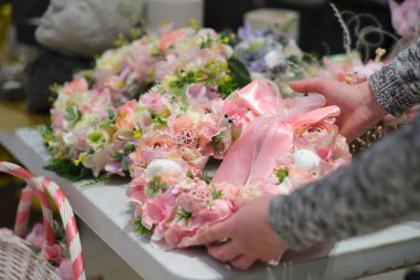 Dükkan sahibi, yerel bir zanaatkar pazarında elinde bir buket kurumuş çiçekle tezgahın arkasında satış yapıyor. Küçük bir iş. Genç bayan girişimci çiçek bayramı kompozisyonu satıyor..