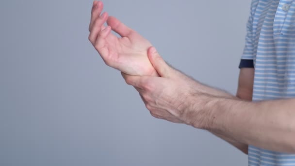 사람은 자신을 붓으로 붙잡고 심한 고통을 느낀다. 남자 팔 이 그 의 고통 스러운 손목을 잡고 있는 것은 컴퓨터, 노트북 에서의 오랜 작업으로 인한 것입니다. 비디오 스토리지 영상. 느린 동작 — 비디오