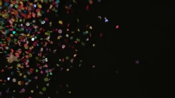 Närbild Confetti explosion på svart bakgrund. Slow Motion konfetti faller video. Flerfärgspartiklar som flyger efter att ha exploderat — Stockvideo