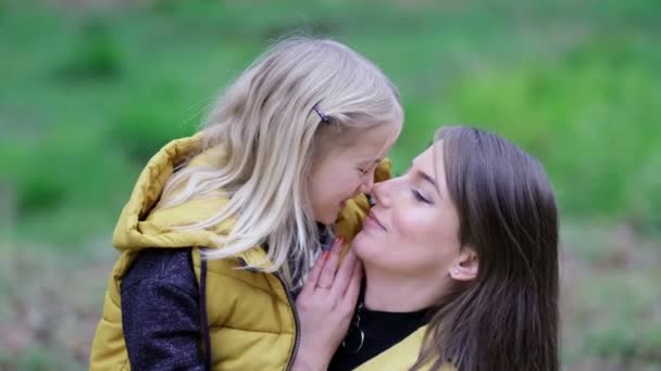 Beijar e abraçar a família feliz. Mãe bonita e sua filhinha ao ar livre. Natureza. A mãe da beleza e o seu filho a brincar no parque juntos. filmagens de vídeo. Foco suave em câmera lenta — Vídeo de Stock