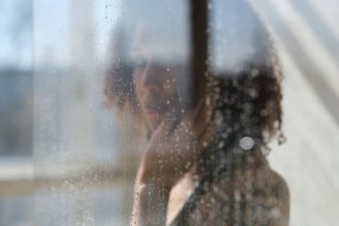 Duş kabininde poz veren genç bir kadın modelin odaklanmış görüntüsü. Huzurlu bir kadın. Ruhun iyileşmesi. Ruhani uygulama. Esrarengiz gizem.