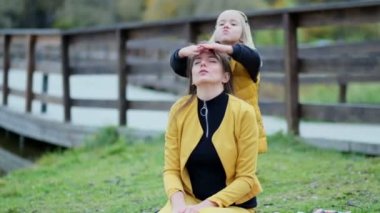 Mutlu aileyi öpmek ve kucaklamak. Güzel anne ve küçük kızı dışarıda. Doğa. Güzel anne ve çocuğu parkta birlikte oynuyorlar. Video kayıtları. Yavaş çekim yumuşak odak