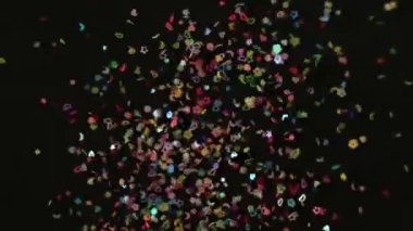 Konfeti patlamasını siyah arkaplanda kapat. Slow Motion konfetisi düşen video. Patlamadan sonra uçan çok renkli parçacıklar