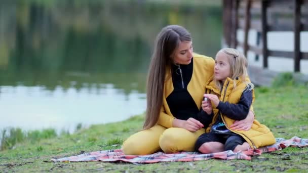 Hermosa joven y su encantadora hijita se divierten en el parque. Hija abrazando a la madre en la naturaleza. Vídeo en cámara lenta. material de archivo — Vídeo de stock