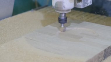 Tahta değirmeni. CNC 'deki ahşap panellerin işlenmesi koordine edilmiş marangozluk makineleri. Yavaş çekim videosu. Talaş farklı yönlere dağılır.