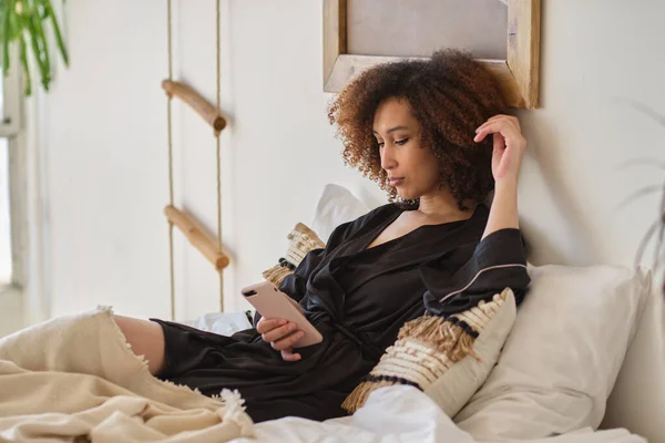 Fiatal gyönyörű afro-amerikai nő sms-ezés okostelefonon, vagy nézi a szociális hálózat. — Stock Fotó