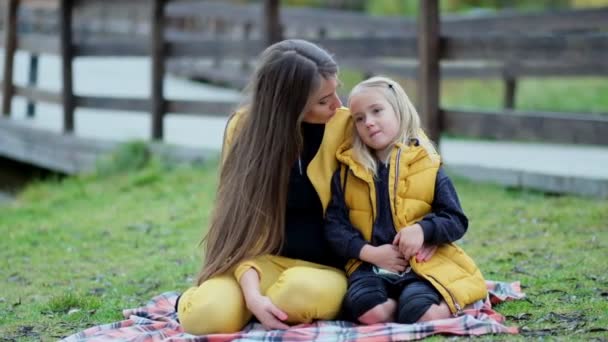 Mulher bonita e sua filhinha encantadora se divertem no parque. Filha abraçando a mãe na natureza. Vídeo em câmara lenta. imagens de stock — Vídeo de Stock