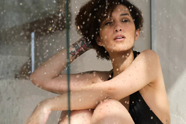 Retrato sensual de una joven duchándose. Mujer desenfocada mira a través del vidrio de la cabina de ducha. Retrato de arte. Belleza femenina. Bienestar del cuidado de la piel. — Foto de Stock