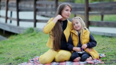 Mutlu aileyi öpmek ve kucaklamak. Güzel anne ve küçük kızı dışarıda. Doğa. Güzel anne ve çocuğu parkta birlikte oynuyorlar. Video kayıtları. Yavaş çekim yumuşak odak