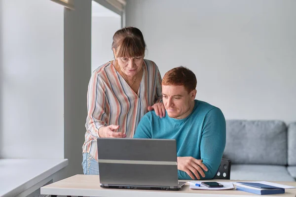 stock image Young Man showing how to use computer to an old woman. elders technology concept. Middle aged man helping his mother use a laptop computer at home, close up