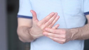 Bir adam elinde bir eklem masajı yapar. Kapatın. Karpal tünel sendromu, artrit, nörolojik hastalık konsepti. Elin uyuşması. Video kayıtları. Yavaş çekim, yumuşak odaklanma