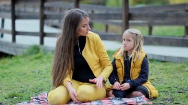 Güzel genç bir kadın ve büyüleyici küçük kızı parkta eğleniyor. Doğada annesine sarılan bir kız. Yavaş çekim videosu. depolama görüntüleri