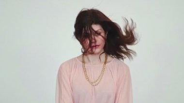 Uzun kıvırcık saç stili, dans eden ve gülümseyen cilveli Meksikalı güzel bir kadının yakın çekimi. İyi haberi kutluyor, beyaz arka planda duruyor..