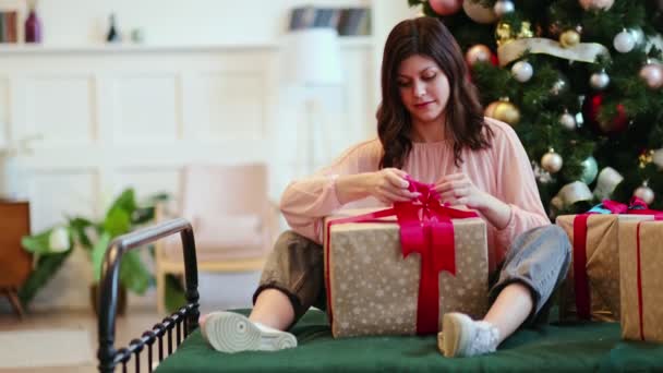 Όμορφη νεαρή γυναίκα ανοίγει κουτί δώρου στο σπίτι. Χριστουγεννιάτικη γιορτή — Αρχείο Βίντεο