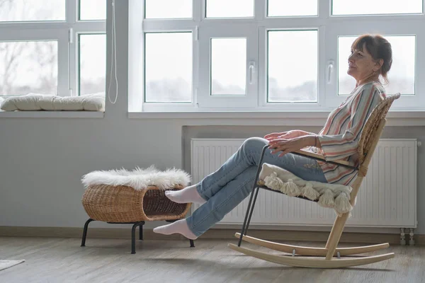 Yaşlı kadın hasır sallanan bir sandalyede oturuyor. Kadın koltukta dinleniyor. Hayatın neşesi — Stok fotoğraf