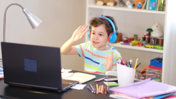 Speelse jongen begroet zijn leraar voor een online les. online les thuis, sociale afstand tijdens quarantaine, zelf-isolatie, online onderwijs concept — Stockvideo