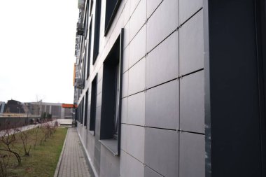 Pencereli metal plakalardan yapılmış ofis binası duvarı. Seramik havalandırmalı cephedeki modern konut pencerelerinin ayrıntıları.