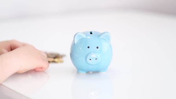 Child hand is putting a coin in a lifestyle piggy bank on a yellow background. saving money is an investment for the future. Banking investment — Stock Video