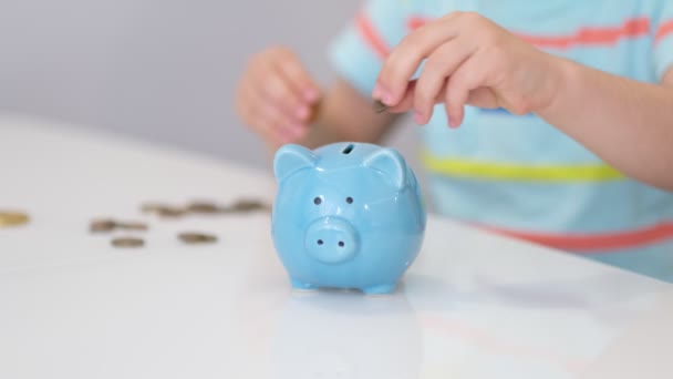 A mão da criança está pondo uma moeda em um banco piggy do estilo de vida em um fundo amarelo. poupar dinheiro é um investimento para o futuro. Investimento bancário — Vídeo de Stock