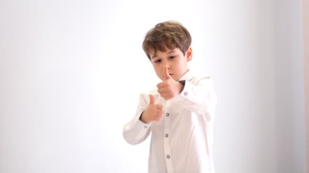 Seorang anak dalam kemeja putih memberikan jempol-up. Anak kecil senang dan menari. — Stok Video