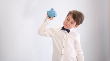 Beyaz kravatlı Asyalı küçük çocuk boş bir kumbarayı sallıyor, para kavramı yok, finansman için çocuksu tavırlar.