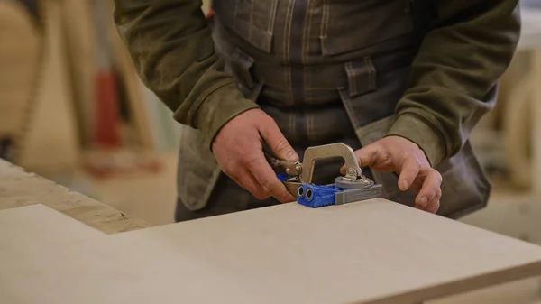Kapatın. Marangoz atölyede çalışıyor. Ahşap işleri ve mobilya yapma konsepti. Atölyedeki marangoz mobilya dolabının parçalarını işaretleyip monte ediyor. — Stok fotoğraf