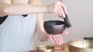 Kadın yoga minderinde otururken Tibet şarkı kasesinde oynuyor. Antika tonlu. Stok görüntüleri. Slow Motion videosu. Kapat.