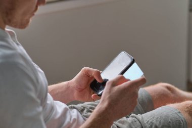 Evdeki akıllı telefondan kredi kartıyla ödeme yapan tanınmamış bir adam. Çevrimiçi ödeme. Cep telefonundan alışveriş yap. Mans bir kredi kartı tutuyor ve online alışveriş için akıllı telefon kullanıyor