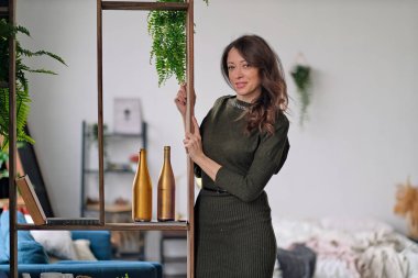 Dairesinde kendine güvenen bağımsız bir kadın. Bir fotoğraf için poz vermek. Güzel bir bayanın portresi. Gülümseyen kadın kameraya bakıyor..