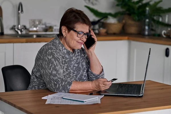 Modern old cheerful lady using online banking. Frustrated senior woman yelling at the bank clerk, dissatisfied with her credit card balance.