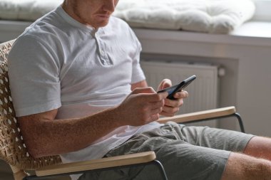 Evdeki akıllı telefondan kredi kartıyla ödeme yapan tanınmamış bir adam. Çevrimiçi ödeme. Cep telefonundan alışveriş yap. Mans bir kredi kartı tutuyor ve online alışveriş için akıllı telefon kullanıyor