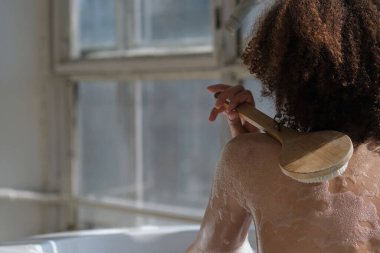 Gülümseyen ve rahatlatan Afro-Amerikan kadın köpük dolu bir küvette banyo yapıyor. Harika bir zaman. Yaşam tarzı insan kavramı