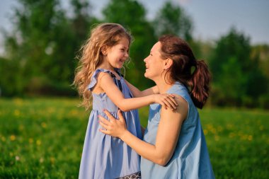 Açık havada aile hayatı olan bir doğa sahnesi. Anne ve küçük kızı parkta birlikte oynuyorlar. Mutlu aile kavramı. Aile hayatında mutluluk ve uyum..