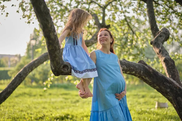 Adorable petite fille et sa mère enceinte profitant de son temps dans le parc par une journée d'été chaude et ensoleillée. Enfant qui s'amuse en vacances scolaires. — Photo