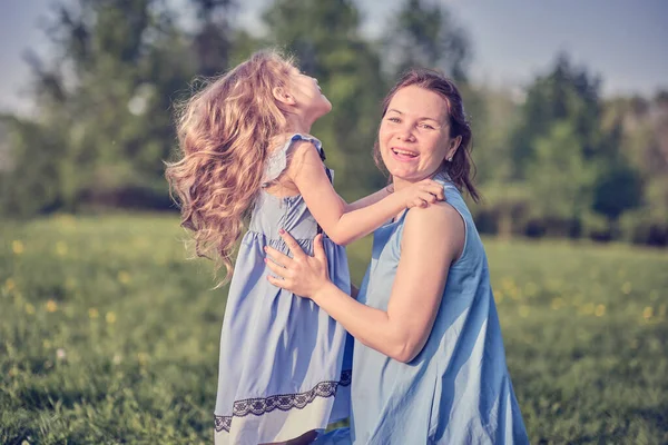 Naturszene mit familiärem Outdoor-Lifestyle. Mutter und kleine Tochter spielen zusammen in einem Park. Glückliches Familienkonzept. Glück und Harmonie im Familienleben. — Stockfoto