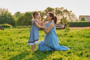 Açık havada aile hayatı olan bir doğa sahnesi. Anne ve küçük kızı parkta birlikte oynuyorlar. Mutlu aile kavramı. Aile hayatında mutluluk ve uyum..