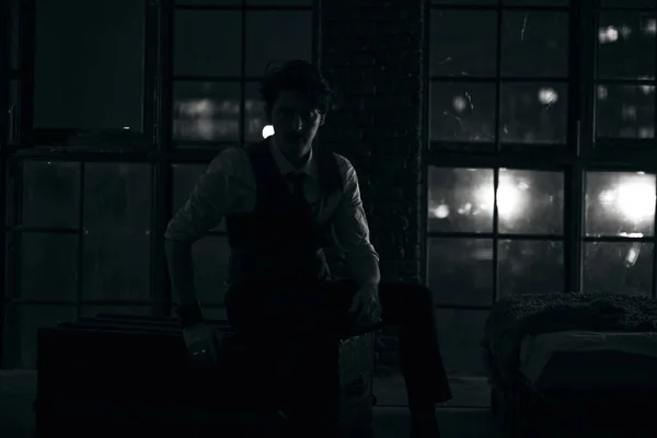 Stylowy ubrany mężczyzna stoi przy oknie i patrzy w oddali. zamyślony mężczyzna stoi w nocy w ciemnym pokoju — Zdjęcie stockowe