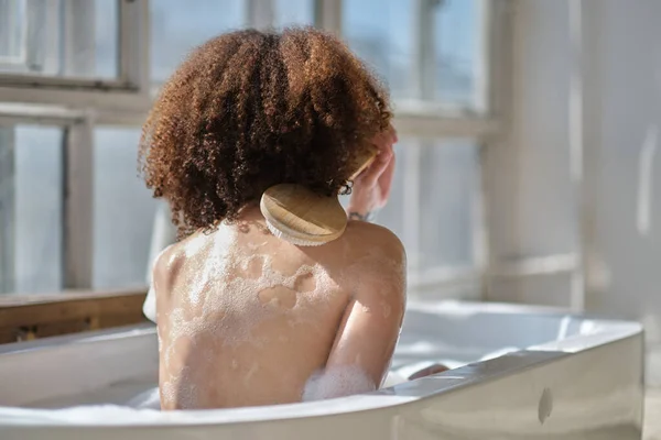Lachende en ontspannende Afro-Amerikaanse vrouw badend in een bad vol schuim. Geweldige tijd. levensstijl mensen concept — Stockfoto