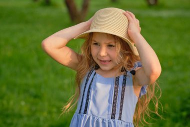 Genç bir kızın portresi, dışarıda saman şapkalı güzel bir çocuk sıcak bir günün tadını çıkarıyor.