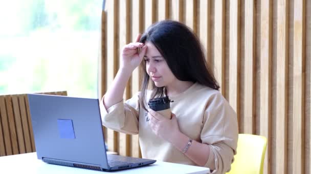 Jeune femme hipster assis dans le café, boire du café et en utilisant un ordinateur portable.Sur la table est un ordinateur portable. Fille naviguant sur Internet, bavarder, blogging. — Video