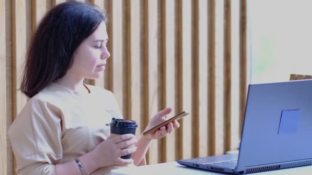 Mulher jovem hipster sentado no café, beber café e usando laptop.On mesa é laptop. Menina navegando na internet, conversando, blogging. — Vídeo de Stock