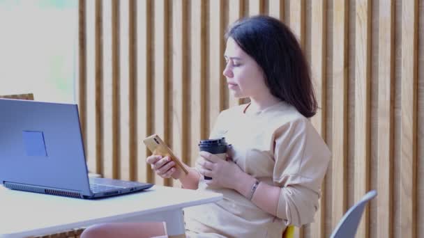 Joven mujer hipster sentado en el café, beber café y el uso de laptop.On mesa es portátil. Chica navegando por Internet, chatear, bloguear. — Vídeo de stock